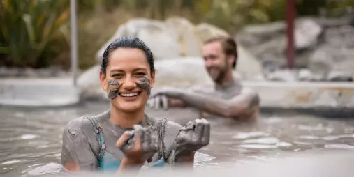 Woman smiling while enjoying a mud pool session at Hell’s Gate in Rotorua.