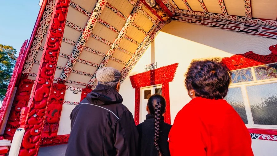 Visitors admiring intricate Māori carvings at a marae during a Kahukiwi cultural tour in Rotorua.