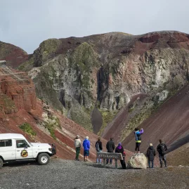 Group at a lookout point over the Mount Tarawera crater, with 4WD vehicle parked nearby.