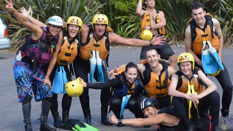 Sledging group posing together in wetsuits and helmets after an adventure on the Kaituna River.
