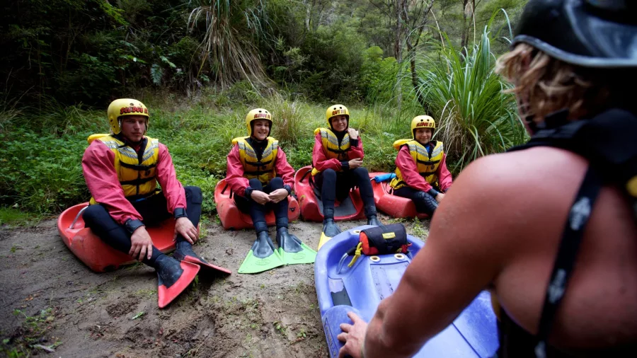 Instructor giving a safety briefing to sledging participants on the riverbank at Kaituna.