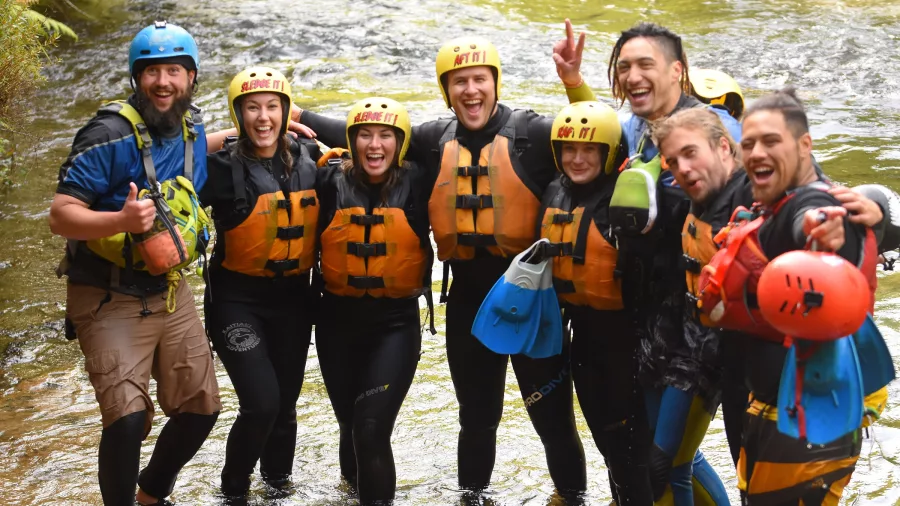 Sledging group posing together in the river after their white-water adventure.