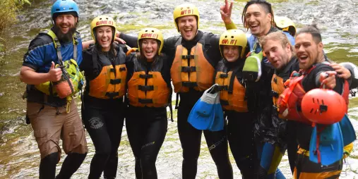 Sledging group posing together in the river after their white-water adventure.