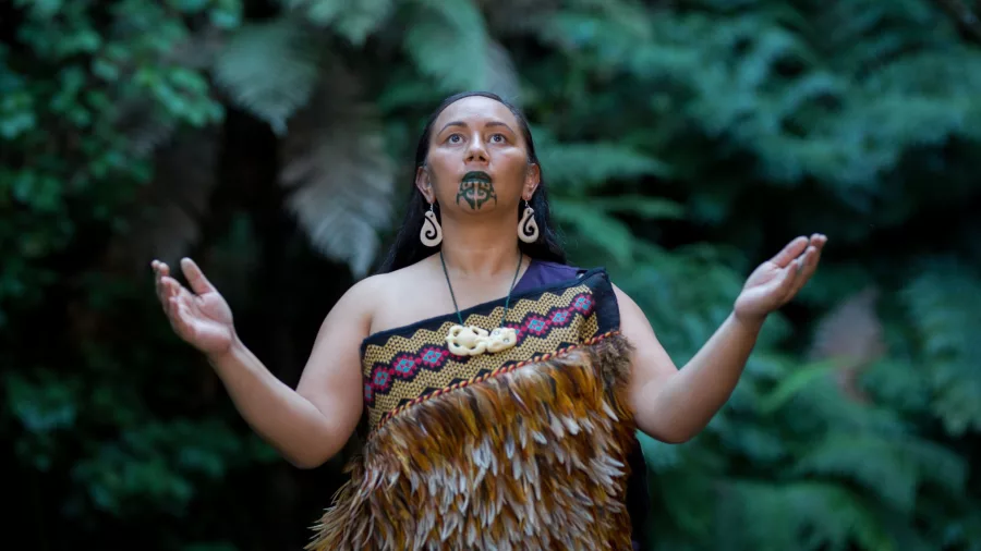 Māori woman performing a traditional karanga welcome call at Mitai Māori Village in Rotorua, New Zealand.