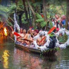 Māori warriors arriving in a waka (canoe) during the cultural show at Mitai Māori Village.