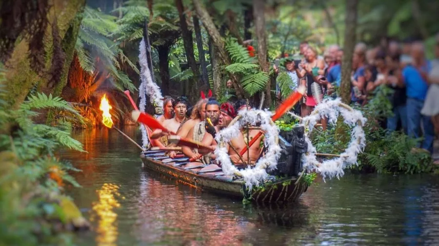 Māori warriors arriving in a waka (canoe) during the cultural show at Mitai Māori Village.