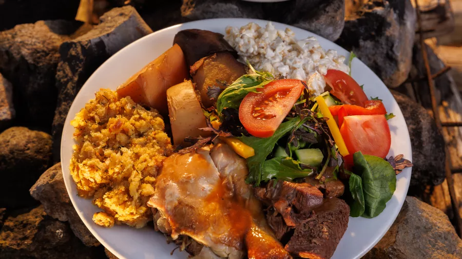 Traditional Māori hāngī meal served on hot rocks at Mitai Māori Village in Rotorua.