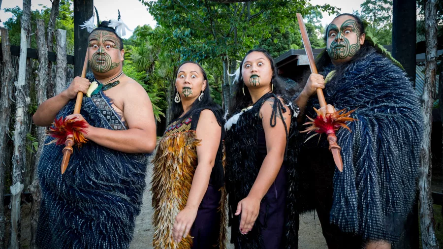 Māori whānau (family) dressed in traditional attire standing together at Mitai Māori Village in Rotorua.