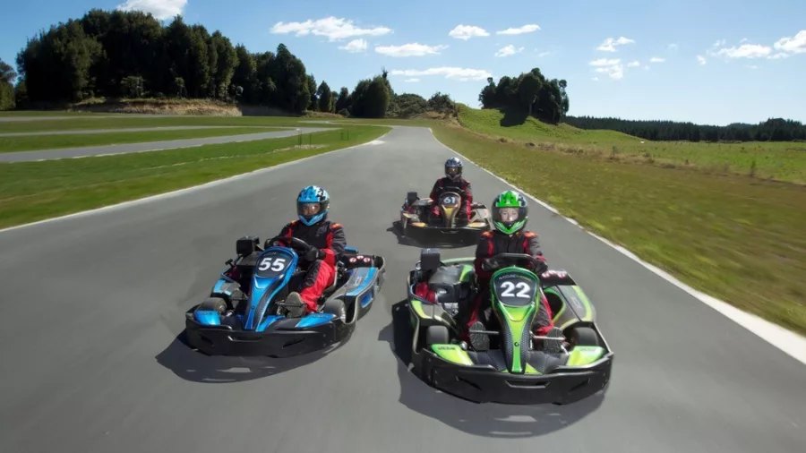 Three go-kart drivers racing side by side on the Raceline Karting circuit in Rotorua.