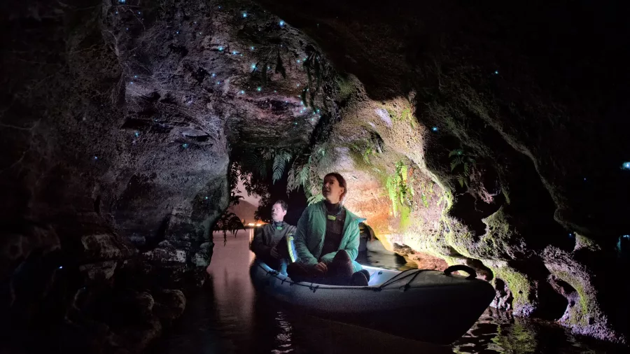Couple in a kayak exploring an illuminated glow worm cave in Rotorua.