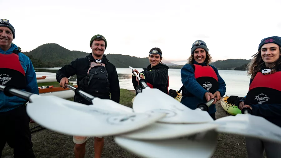Group of kayakers smiling with paddles ready before their glow worm adventure in Rotorua.