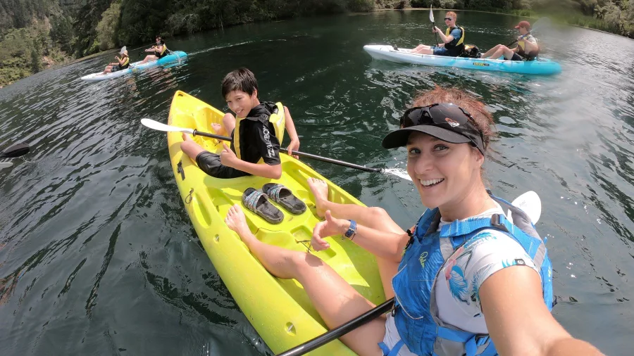 Smiling kayakers enjoying the geothermal lake during a family tour in Waimangu Valley.