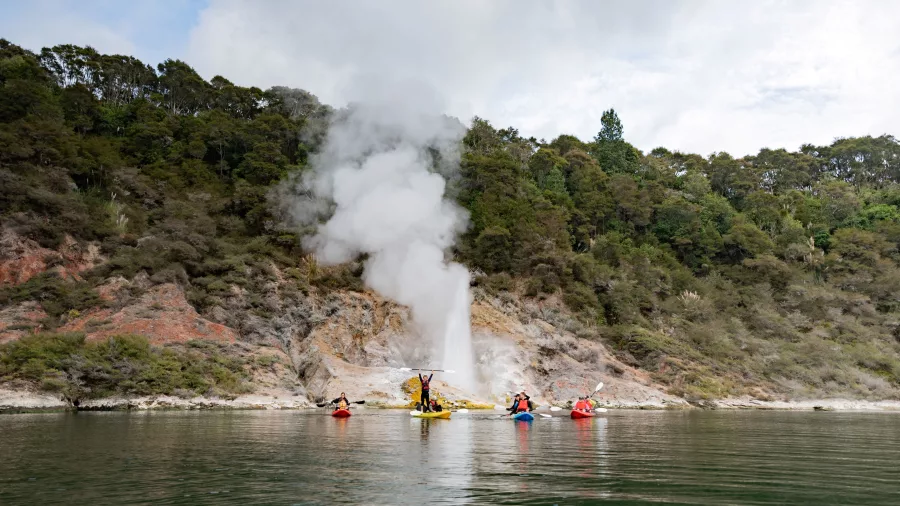Kayakers arriving at a geothermal geyser erupting from the edge of Lake Rotomahana.