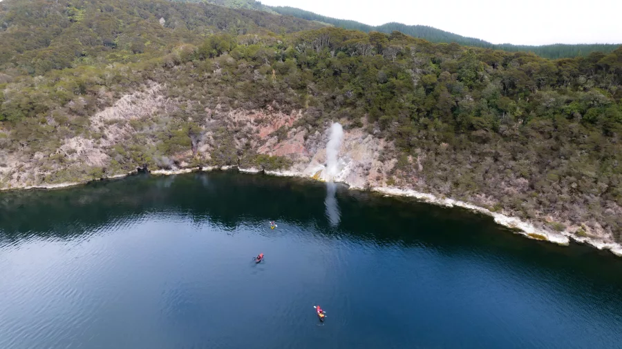 Aerial view of kayakers heading towards a steaming geyser on Lake Rotomahana.