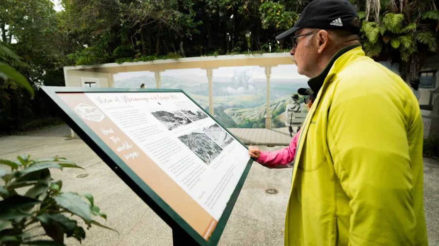 Visitor reading interpretive signage on the Waimangu Valley self-guided geothermal walk.