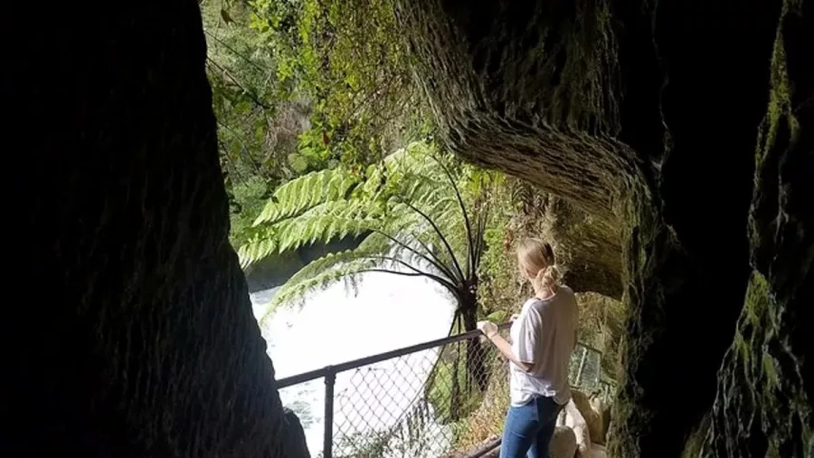 Visitor standing at a lookout in the cave tunnel above Okere Falls in Rotorua.