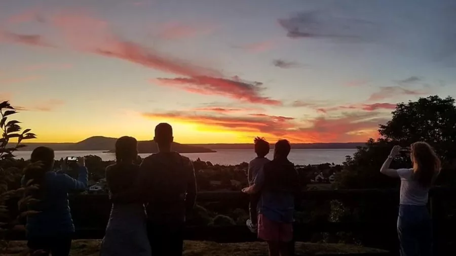 Silhouetted group watching sunset over Lake Rotorua from Mount Ngongotahā.