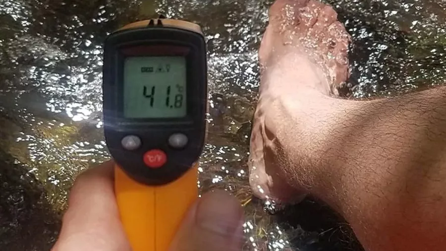 Temperature reading of 41.8°C next to a foot soaking in a natural hot stream in Rotorua
