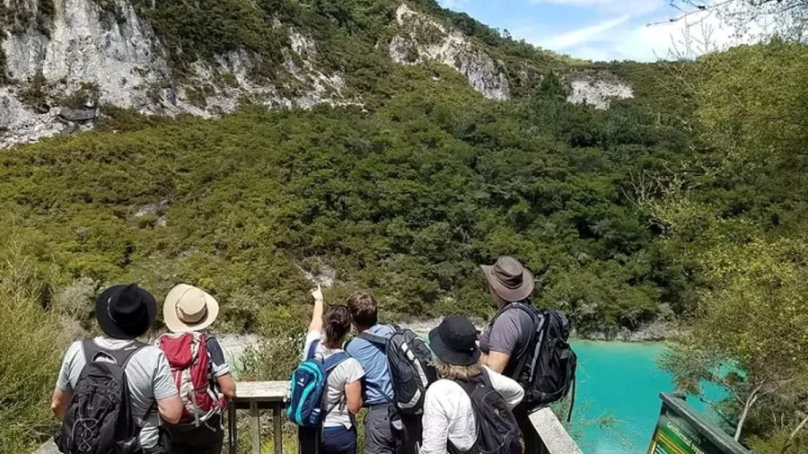 Group of hikers looking out over the turquoise crater lake at Rainbow Mountain near Rotorua.