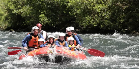 Family rafting together on the Lower Rangitāiki River with big smiles and paddles ready.
