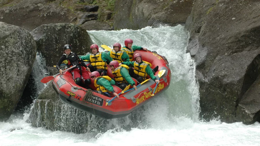 Raft launches off a narrow chute between boulders on the Wairoa River with River Rats.