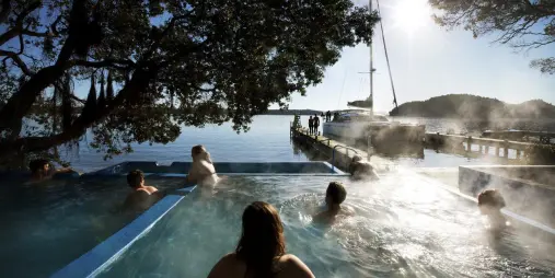 Guests soaking in lakeside hot pools at Lake Rotoiti