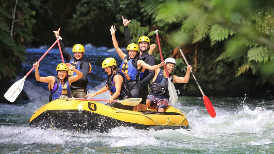 Group cheering and paddling down white water with Rotorua Rafting