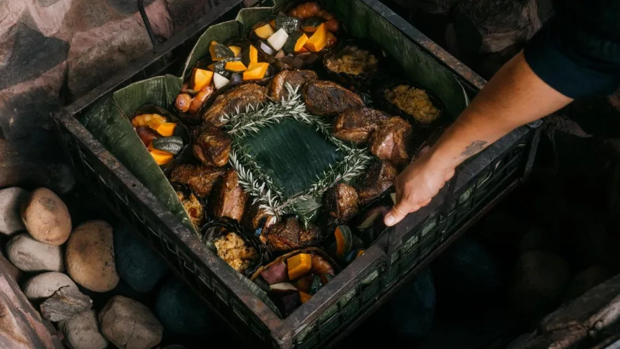 Traditional Māori hāngī being lifted from an earth oven at Te Pā Tū
