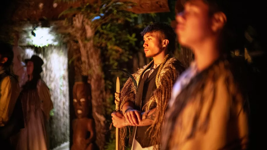 Young Māori warrior illuminated by firelight during Te Pā Tū evening ceremony