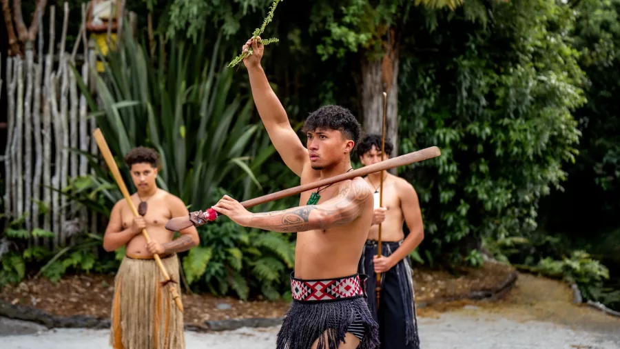 Māori warrior performing the wero challenge with a fern during Te Pā Tū pōwhiri