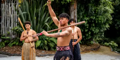 Māori warrior performing the wero challenge with a fern during Te Pā Tū pōwhiri