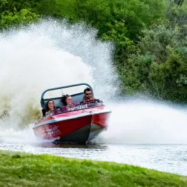 Jet boat kicking up water as it powers through a tight corner at Velocity Valley
