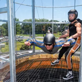 Instructor assisting a participant in stable flight position inside the wind tunnel