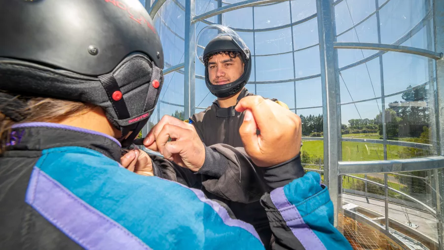 Freefall Xtreme instructor helping a visitor prepare for wind tunnel flight in Rotorua