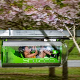 Single rider powering through a clear Shweeb pod along the monorail track