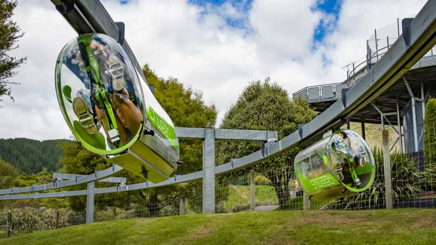 Two Shweeb pods racing side by side on a suspended monorail track in Rotorua