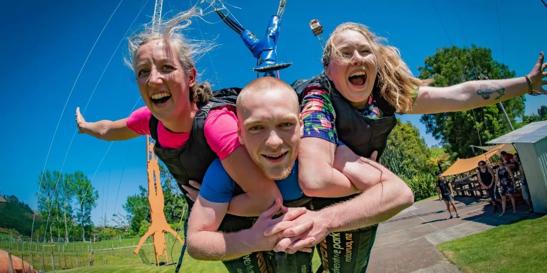 Group of three riders mid-launch on the Swoop swing at Velocity Valley in Rotorua
