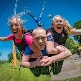 Group of three riders mid-launch on the Swoop swing at Velocity Valley in Rotorua