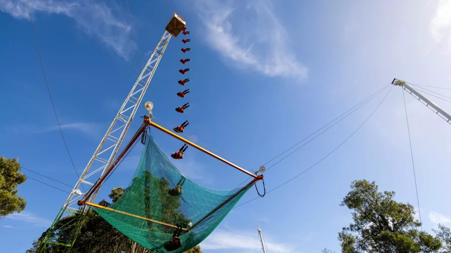 Rider dropping from a tall tower onto a giant net at Vertigo, Velocity Valley Rotorua