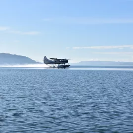 Otter floatplane taking off across the waters of Lake Rotorua with Mokoia Island in the distance