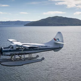 Volcanic Air floatplane flying over Lake Rotorua with Mokoia Island in the distance