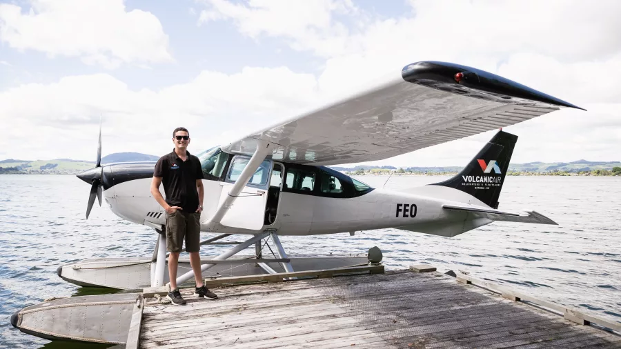Volcanic Air pilot standing next to a Cessna floatplane at the Rotorua lakefront jetty