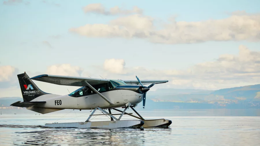Volcanic Air Cessna floatplane floating peacefully on Lake Rotorua under soft morning skies