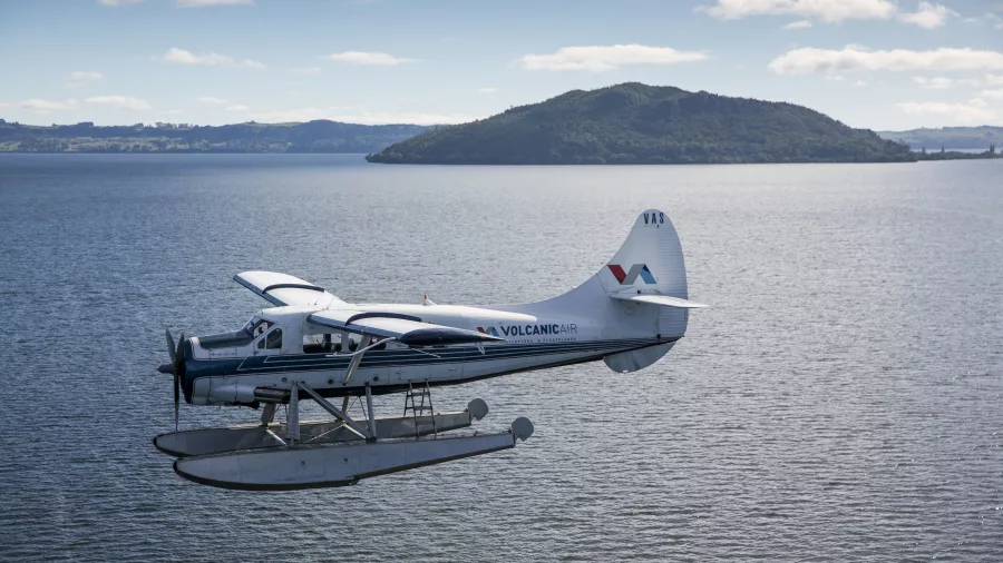 Volcanic Air floatplane flying over Lake Rotorua with Mokoia Island in the distance