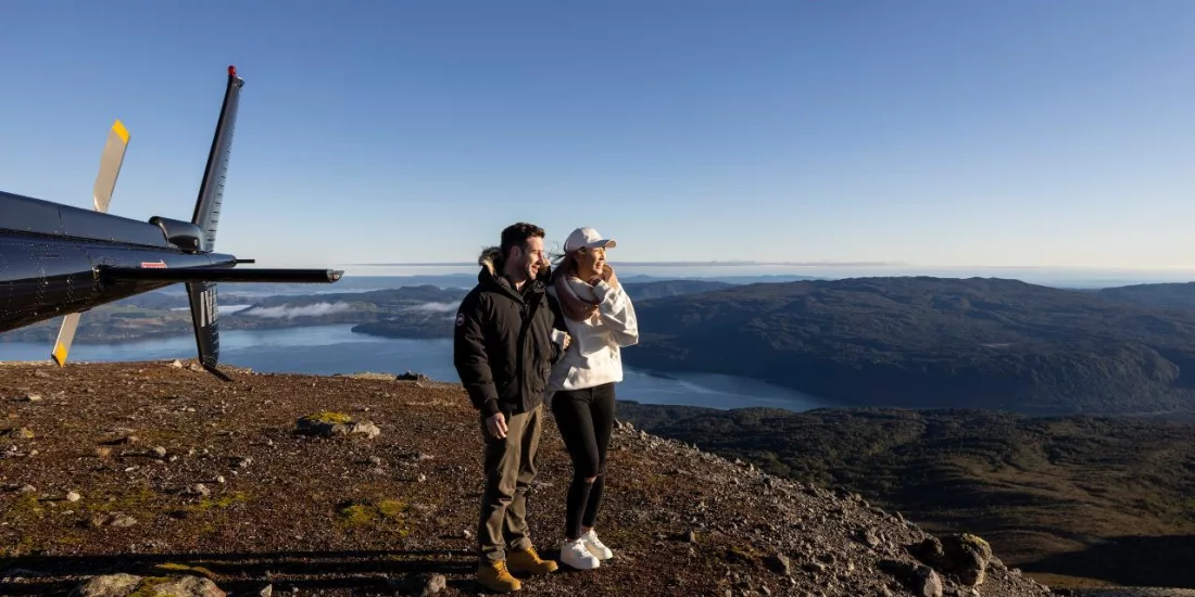 Couple standing near a helicopter on Mount Tarawera summit