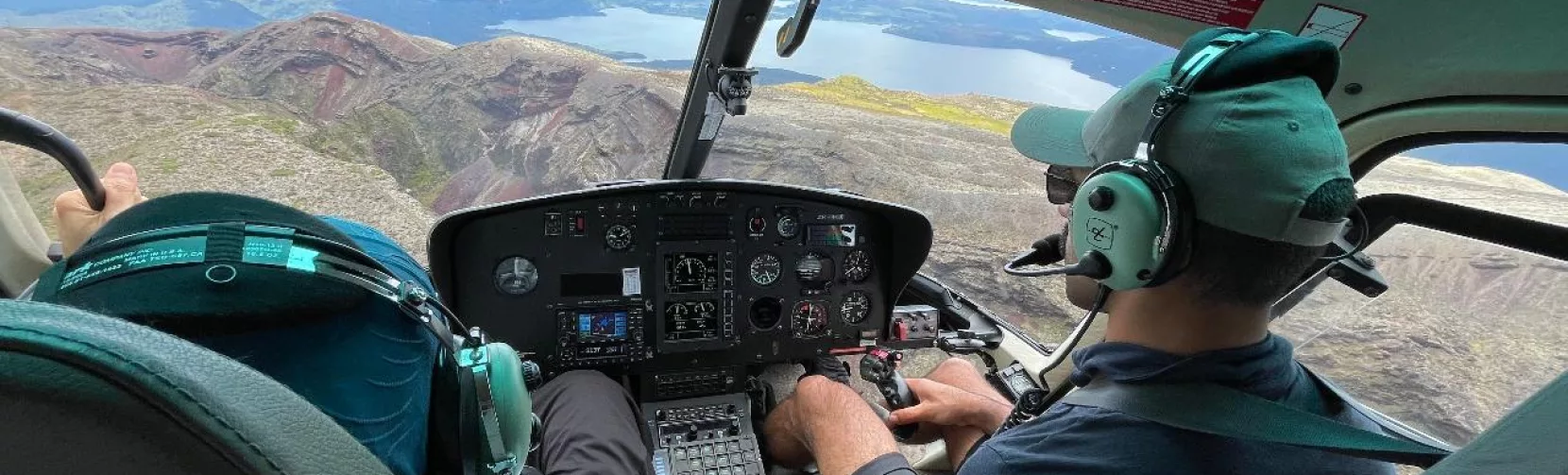 View from helicopter cockpit flying over Mount Tarawera crater and Lake Tarawera