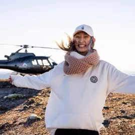 Smiling woman standing in front of a helicopter on Mount Tarawera summit