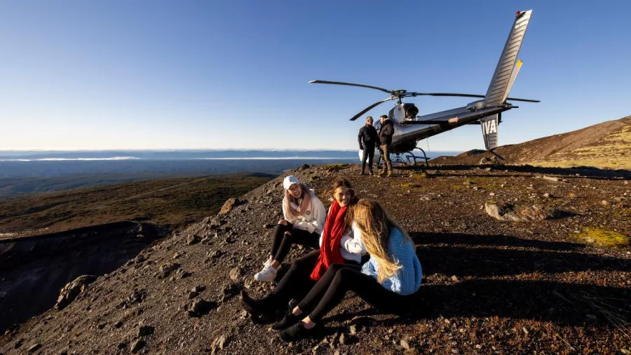Friends relaxing near their helicopter with sweeping views across Mount Tarawera