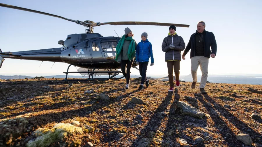 Small group walking away from a landed helicopter on Mount Tarawera’s summit