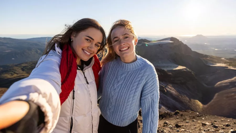 Two friends taking a selfie with the volcanic landscape of Mount Tarawera behind them